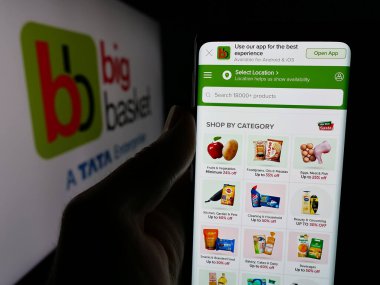 Stuttgart, Almanya - 10-28-2024: Hintli online market şirketi BigBasket 'in web sayfası ile logo önünde akıllı telefon tutan kişi. Telefon ekranının merkezine odaklan.