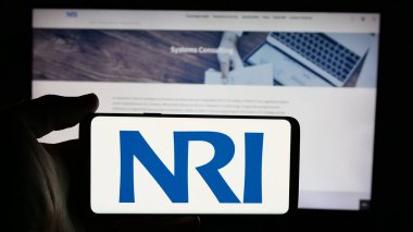 Stuttgart, Almanya - 10-28-2024: İnternet sayfası önünde üzerinde Nomura Araştırma Enstitüsü Ltd. (NRI) logosu bulunan cep telefonu sahibi kişi. Telefon ekranına odaklan.