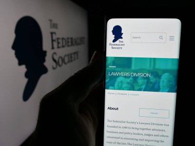 Stuttgart, Almanya - 10-28-2024: ABD hukuk örgütü Federalist Toplumu 'nun logo önündeki web sayfası ile cep telefonu tutan kişi. Telefon ekranının merkezine odaklan.