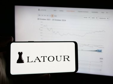 Stuttgart, Germany - 10-28-2024: Person holding mobile phone with logo of Swedish company Investment AB Latour on screen in front of business web page. Focus on phone display. clipart