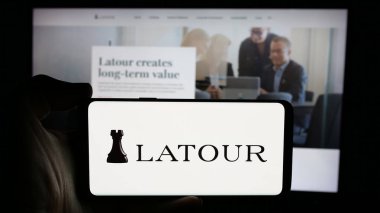 Stuttgart, Almanya - 10-28-2024: İsveç şirketi Investment AB LaTour 'un logosuyla cep telefonu sahibi kişi iş sayfası önünde ekranda. Telefon ekranına odaklan.
