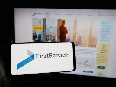 Stuttgart, Almanya - 10-30-2024: Kanadalı firma First Service Corporation 'ın logosunu elinde tutan kişi web sitesinin önünde ekranda. Telefon ekranına odaklan.