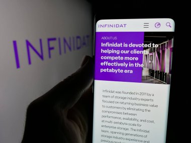Stuttgart, Almanya - 10-31-2024: Veri depolama şirketi Infinidat Ltd. 'nin web sayfası ile cep telefonu tutan kişi logonun önünde ekranda. Telefon ekranının merkezine odaklan.