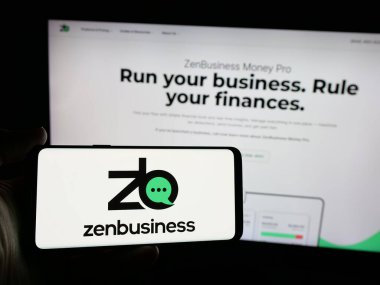 Stuttgart, Almanya - 10-31-2024: ABD 'li ZenBusiness Inc. şirketinin logosunu elinde tutan kişi web sitesinin önünde ekranda. Telefon ekranına odaklan.