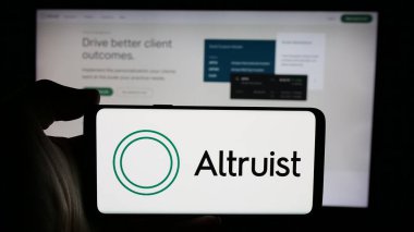 Stuttgart, Almanya - 10-31-2024: ABD 'li fintech şirketi Altruist Corp' un logosunu taşıyan cep telefonu şirketinin sahibi iş sitesinin önünde ekranda. Telefon ekranına odaklan.