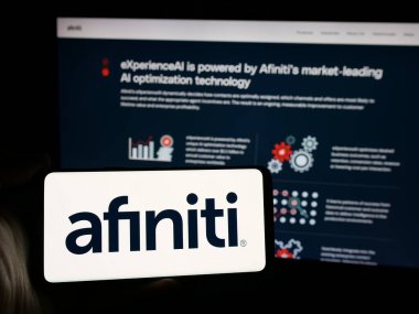 Stuttgart, Almanya - 10-31-2024: Web sitesinin önünde ekranda üzerinde yapay zeka yazılım şirketi Afiniti Ltd. 'nin logosu olan cep telefonu bulunan kişi. Telefon ekranına odaklan.