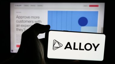 Stuttgart, Almanya - 10-31-2024: İnternet sayfası önünde üzerinde ABD kimlik risk şirketi First Mile Group Inc. (Alloy) logosu bulunan kişi. Telefon ekranına odaklan.