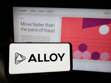Stuttgart, Almanya - 10-31-2024: İnternet sitesi önünde üzerinde ABD kimlik risk şirketi First Mile Group Inc. (Alloy) logosu bulunan akıllı telefon sahibi kişi. Telefon ekranına odaklan.