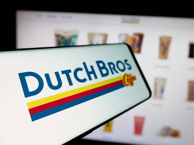 Stuttgart, Almanya - 11-06-2024: Amerikan kahve zinciri şirketi Dutch Bros Inc. 'in logosunun yer aldığı cep telefonu iş sitesinin önünde ekranda. Telefon ekranının soluna odaklan.