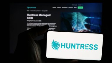 Stuttgart, Almanya - 11-06-2024: İnternet sitesinin önünde ekranda Amerikan siber güvenlik şirketi Huntress Labs Inc. 'in logosu olan cep telefonu sahibi kişi. Telefon ekranına odaklan.