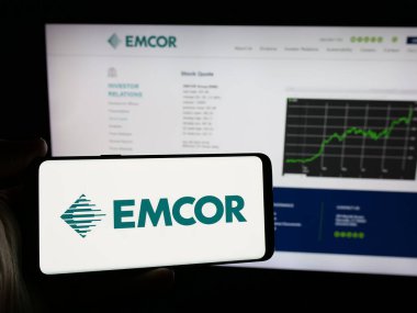 Stuttgart, Almanya - 11-07-2024: İnternet sitesi önünde ekranda ABD 'li mühendislik şirketi EMCOR Group Inc.' nin logosuna sahip akıllı telefonu tutan kişi. Telefon ekranına odaklan. 