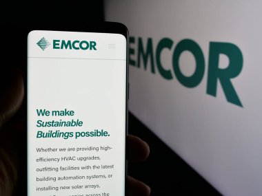 Stuttgart, Almanya - 11-07-2024: ABD 'li mühendislik şirketi EMCOR Group Inc.' nin web sayfası ile akıllı telefon sahibi kişi logonun önünde ekranda. Telefon ekranının merkezine odaklan. 