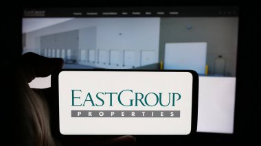 Stuttgart, Almanya - 11-07-2024: ABD 'li REIT şirketi EastGroup Properties Inc.' in logosuyla cep telefonu sahibi kişi iş sayfasının önünde ekranda. Telefon ekranına odaklan. 