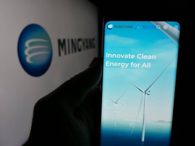 Stuttgart, Almanya - 11-07-2024: Çinli şirket Ming Yang Wind Power Group Limited 'in internet sayfası ile cep telefonu tutan kişi logo ile ekranda. Telefon ekranının merkezine odaklan.
