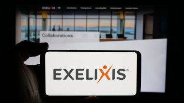 Stuttgart, Almanya - 11-07-2024: Üzerinde ABD 'li biyoteknoloji şirketi Exelixis Inc.' in logosu olan cep telefonu sahibi kişi iş sayfasının önünde ekranda. Telefon ekranına odaklan.