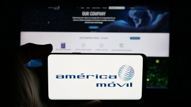 Stuttgart, Almanya - 11-08-2024: Meksikalı Movil S.A.B. şirketinin logosuyla cep telefonu tutan kişi De C.V. iş sayfasının önünde ekranda. Telefon ekranına odaklan.
