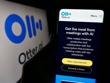 Stuttgart, Almanya - 12-27-2023: ABD 'li yapay istihbarat şirketi Otter.ai Inc.' in web sayfası ile logo önünde cep telefonu tutan kişi. Telefon ekranının merkezine odaklan.