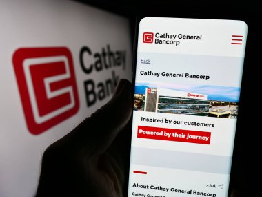Stuttgart, Almanya - 12-23-2023: Logo önünde ABD 'li Cathay General Bancorp (Cathay Bank) şirketinin web sayfası ile akıllı telefon tutan kişi. Telefon ekranının merkezine odaklan.