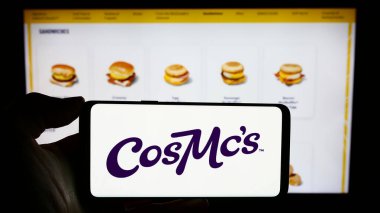 Stuttgart, Almanya - 12-28-2023: Üzerinde ABD 'li fast food zinciri şirketi CosMc' in (McDonalds) logosu olan cep telefonu sahibi kişi iş sayfasının önünde. Telefon ekranına odaklan.