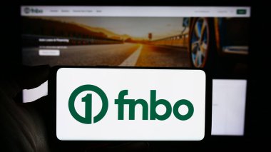 Stuttgart, Almanya - 12-28-2023: ABD 'li finans şirketi First National Bank Omaha' nın (FNBO) logosuyla cep telefonu sahibi kişi iş sayfası önünde. Telefon ekranına odaklan.