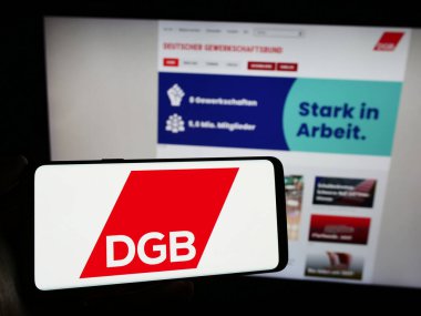 Stuttgart, Almanya - 12-29-2023: Alman örgütü Deutscher Gewerkschaftsbund 'un (DGB) logosuna sahip kişi web sitesinin önünde. Telefon ekranına odaklan.