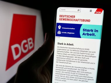 Stuttgart, Almanya - 12-29-2023: Alman örgütü Deutscher Gewerkschaftsbund 'un (DGB) logolu web sayfası ile akıllı telefon tutan kişi. Telefon ekranının merkezine odaklan.