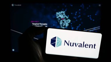 Stuttgart, Almanya - 12-29-2023: ABD 'li biyoteknoloji şirketi Nuvalent Inc.' in logosuna sahip akıllı telefon sahibi kişi web sitesinin önünde. Telefon ekranına odaklan.