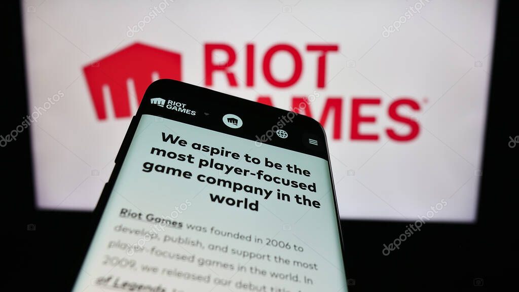 Stuttgart, Germany - 12-27-2023: Mobile phone with website of US video game development company Riot Games Inc. in front of business logo. Focus on top-left of phone display.