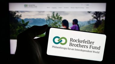 Stuttgart, Almanya - 12-29-2023: Amerikan vakfı Rockefeller Kardeşler Fonu 'nun (RBF) logosunu web sayfasının önünde tutan kişi. Telefon ekranına odaklan.