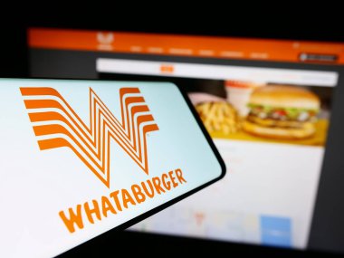 Stuttgart, Germany - 12-31-2023: Smartphone with logo of American fast food company Whataburger Restaurants LLC in front of business website. Focus on center of phone display. clipart