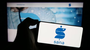 Stuttgart, Almanya - 12-31-2023: Alman sağlık şirketi Sana Kliniken AG 'nin logosuna sahip cep telefonu sahibi kişi iş sayfasının önünde. Telefon ekranına odaklan.
