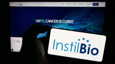 Stuttgart, Almanya - 12-31-2023: ABD 'li biyoteknoloji şirketi Instil Bio Inc.' in logosuna sahip akıllı telefon sahibi kişi web sitesi önünde. Telefon ekranına odaklan.