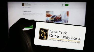 Stuttgart, Almanya - 12-31-2023: İnternet sitesi önünde ABD 'li şirket New York Community Bancorp Inc. (NYCB) logosuna sahip kişi. Telefon ekranına odaklan.