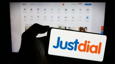 Stuttgart, Germany - 12-31-2023: Person holding smartphone with logo of Indian technology company Just Dial Limited (Justdial) in front of website. Focus on phone display. clipart