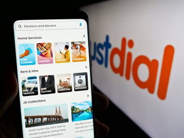 Stuttgart, Almanya - 12-31-2023: Hint teknoloji şirketi Just Dial Limited 'in (Justdial) logolu web sayfası ile cep telefonu tutan kişi. Telefon ekranının merkezine odaklan.