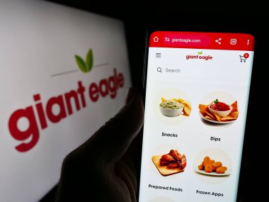 Stuttgart, Almanya - 02-03-2024: Logo önünde ABD 'li süpermarket zincir şirketi Giant Eagle Inc.' in web sayfası ile cep telefonu tutan kişi. Telefon ekranının merkezine odaklan.
