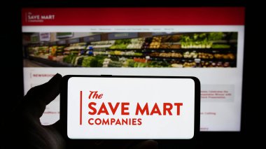 Stuttgart, Almanya - 02-03-2024: ABD 'li süpermarket şirketi The Save Mart Companies' in logosuyla cep telefonu sahibi kişi iş sayfası önünde. Telefon ekranına odaklan.