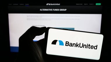 Stuttgart, Almanya - 02-06-2024: İnternet sitesi önünde ABD 'li finans hizmetleri şirketi BankUnited Inc.' in logosuna sahip kişi. Telefon ekranına odaklan.
