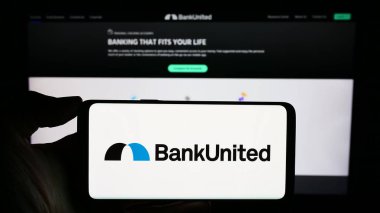 Stuttgart, Almanya - 02-06-2024: ABD 'li finans hizmetleri şirketi BankUnited Inc.' in logosuyla cep telefonu sahibi kişi iş sayfası önünde. Telefon ekranına odaklan.