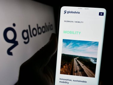 Stuttgart, Almanya - 02-07-2023: İspanyol GLOBALVIA Inversiones S.A.U şirketinin web sayfası ile cep telefonu tutan kişi. Logonun önünde. Telefon ekranının merkezine odaklan.