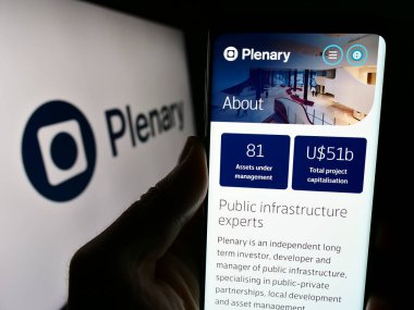Stuttgart, Almanya - 02-07-2023: Avustralyalı altyapı yatırım şirketi Plenary Group 'un logolu web sayfası ile cep telefonu tutan kişi. Telefon ekranının merkezine odaklan.