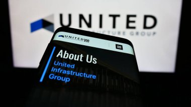 Stuttgart, Almanya - 02-07-2023: İş logosu önünde ABD 'li yatırım şirketi United Infrastructure Group' un web sitesine sahip akıllı telefon. Telefon ekranının sol üst kısmına odaklan.