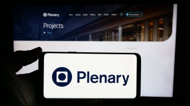 Stuttgart, Almanya - 02-07-2023: İnternet sayfası önünde Avustralyalı altyapı yatırım şirketi Plenary Group 'un logosuyla cep telefonu tutan kişi. Telefon ekranına odaklan.