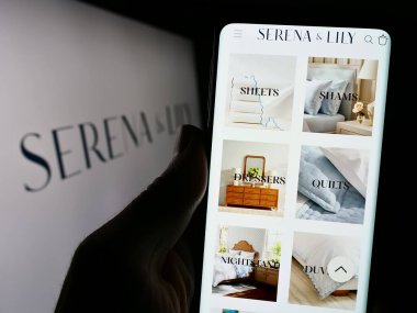 Stuttgart, Almanya - 02-08-2024: ABD 'li ev tasarım şirketi Serena ve Lily Inc.' in web sayfası ile logo önünde akıllı telefon tutan kişi. Telefon ekranının merkezine odaklan.