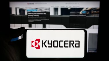 Stuttgart, Almanya - 02-08-2024: Japon elektronik şirketi Kyocera Corporation 'ın logosuna sahip akıllı telefon sahibi kişi web sitesinin önünde. Telefon ekranına odaklan.