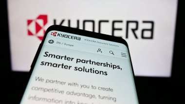 Stuttgart, Almanya - 02-08-2024: Japon elektronik şirketi Kyocera Corporation 'ın web sitesi ile birlikte iş logosu önünde cep telefonu. Telefon ekranının sol üst kısmına odaklan.