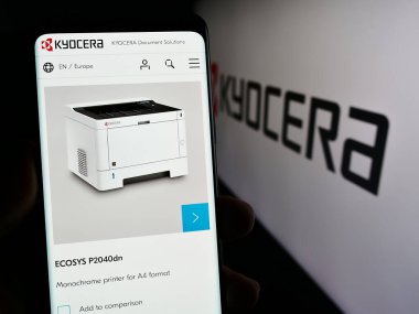 Stuttgart, Almanya - 02-08-2024: Japon elektronik şirketi Kyocera Corporation 'ın internet sayfası ile logo önünde akıllı telefon tutan kişi. Telefon ekranının merkezine odaklan.