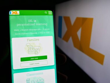 Stuttgart, Almanya - 02-08-2024: ABD çevrimiçi eğitim şirketi IXL Learning Inc. 'in internet sayfası ile logo önünde cep telefonu tutan kişi. Telefon ekranının merkezine odaklan.