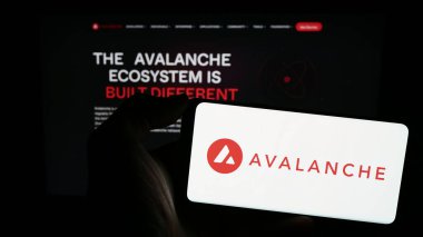 Stuttgart, Almanya - 02-11-2024: İnternet sayfası önünde blockchain şirketi Avalanche (BVI) Inc. (Avax Network) logosu olan cep telefonu sahibi kişi. Telefon ekranına odaklan.