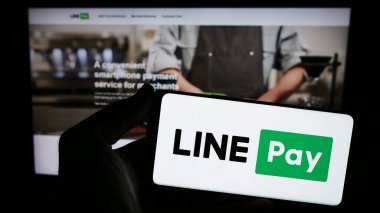 Stuttgart, Almanya - 02-11-2024: Tay ödeme şirketi LINE Pay 'in logosuna sahip akıllı telefon sahibi kişi web sitesi önünde. Telefon ekranına odaklan.